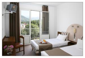 una habitación de hotel con cama y balcón en Adonis Lourdes - Notre Dame de la Sarte, en Lourdes