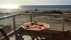 einen Tisch mit Essen auf einem Balkon mit Strand in der Unterkunft Mirasoles 20 in Las Gaviotas