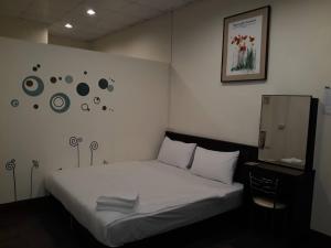 Un dormitorio con una cama blanca y una foto en la pared en Malaya Guest House en Budai