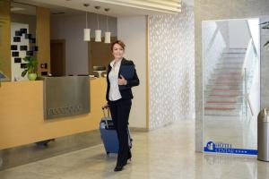 a woman standing in a hallway holding a suitcase at Garni Hotel Centar in Novi Sad