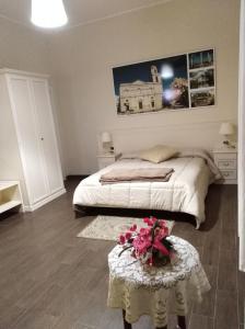 Un dormitorio con una cama y una mesa con flores. en DomuS al Corso con servizio B&B, en Canosa di Puglia