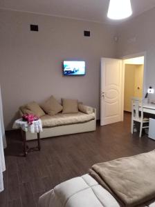 sala de estar con sofá y TV en la pared en DomuS al Corso con servizio B&B, en Canosa di Puglia