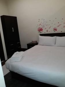 a bedroom with a white bed and a black cabinet at Malaya Guest House in Budai