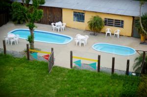 two swimming pools with white chairs and tables at Hotel Glória in São Gabriel