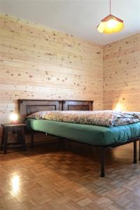 a bed in a room with a wooden wall at Casa del Salice in Carano