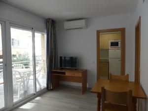 a living room with a table and a television and a balcony at Zeus Alexis in Salou