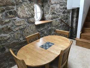 a wooden table and chairs in front of a stone wall at The Stables @ The Old Vicarage in Pendeen