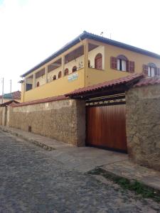 une maison jaune avec un garage en bois dans l'établissement Pousada Caminho da Serra, à Tiradentes