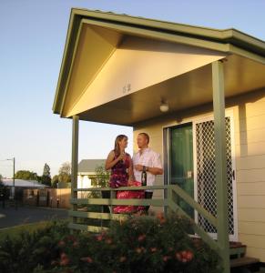 un hombre y una mujer parados en el porche de una casa en PepperTree Cabins, Kingaroy, en Kingaroy
