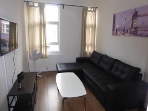 a living room with a black couch and a table at Turnpike House in London