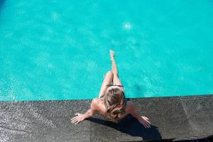 a woman laying on the edge of a swimming pool at Olympic Residence Deluxe Apartments in Limassol