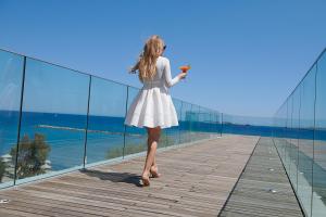 a woman in a white dress standing on a boardwalk at Olympic Residence Deluxe Apartments in Limassol