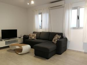 sala de estar con sofá negro y TV en Los Gracioseros BUNGALOW 2, en Puerto del Carmen