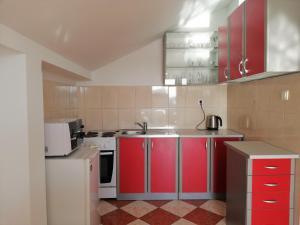 a kitchen with red cabinets and a white stove at Apartment Camellia of Herceg Novi in Bijela