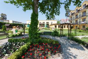 a park with flowers and a tree and buildings at JANTAR-SPA Kompleks Wypoczynkowo-Rehabilitacyjny in Niechorze