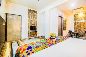 1 dormitorio con 1 cama con colcha colorida en FabExpress Alpine en Agra