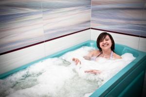 a woman is sitting in a bath tub at JANTAR-SPA Kompleks Wypoczynkowo-Rehabilitacyjny in Niechorze