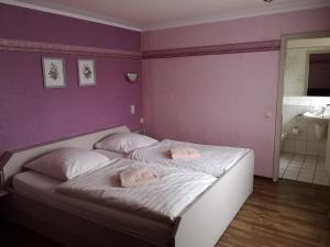 een slaapkamer met een bed met 2 roze kussens erop bij Gasthaus "Zur alten Dorfschmiede" in Metterich