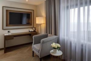 una camera d'albergo con sedia, televisore e tavolo di Foros Health Resort a Foros