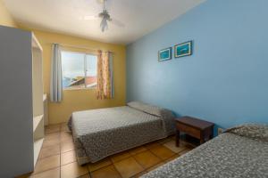 a bedroom with two beds and a window at Residencial Kelly Cristina in Bombinhas