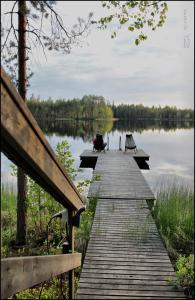 a wooden boardwalk leading to a lake with benches at Kultajärvi Holiday Home in Rastinniemi