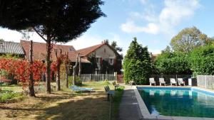 a swimming pool in a yard with chairs and a house at Domaine du Bourg Gites in Gannay-sur-Loire