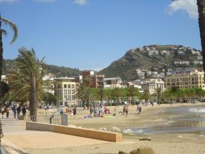 persone su una spiaggia con una montagna sullo sfondo di Apartaments Estudis Els Molins a Roses