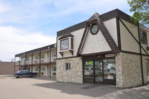 a building with a car parked in a parking lot at Coachman Inn in Regina