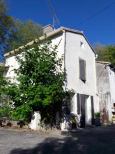 Una casa blanca con un árbol delante. en La Coulée Douce - Chez Antoine en Castelnaudary