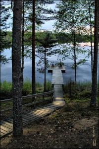 een houten brug over een waterlichaam met bomen bij Kultajärvi Holiday Home in Rastinniemi