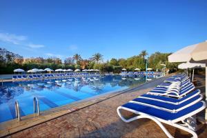 een groot zwembad met blauwe en witte stoelen en parasols bij Valeria Madina Club - All Inclusive in Marrakesh