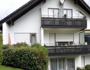 ein weißes Apartmenthaus mit einem Balkon und Büschen in der Unterkunft Wiethegers Ferienwohnungen Gästehaus Centrum II in Willingen