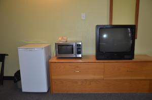 uma televisão e um micro-ondas em cima de uma cómoda em Coachman Inn em Regina