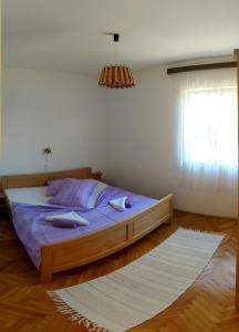 a bedroom with a bed with purple sheets and a window at Apartmani Sandro in Ivan Dolac