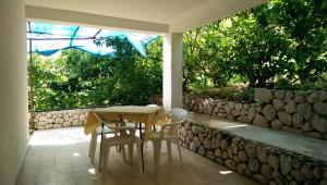 a table and chairs on a patio with a stone wall at Apartmani Sandro in Ivan Dolac