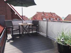 einen Tisch und Stühle auf einem Balkon mit Sonnenschirm in der Unterkunft An´t Möhlen in Carolinensiel