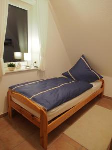 a bedroom with a bed with blue sheets and a window at An´t Möhlen in Carolinensiel