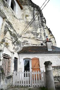 uma casa antiga com uma cerca branca e uma porta de madeira em Les Gîtes des Châteaux, gîtes troglodytiques em Bourré