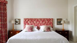 a bedroom with a large white bed with a red headboard at Laurel Cottage in Franschhoek