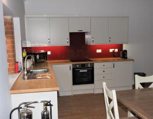 a kitchen with white cabinets and a table with a sink at Nellies Shed, Wolds Way Holiday Cottages, 3 bed spacious cottage in Cottingham +13 photos