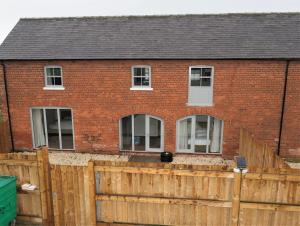 a red brick house with a wooden fence at Nellies Shed, Wolds Way Holiday Cottages, 3 bed spacious cottage in Cottingham