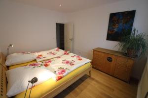 ein Schlafzimmer mit einem Bett und einer Kommode mit einer Blumendecke in der Unterkunft Fewo am Josephsplatz in München