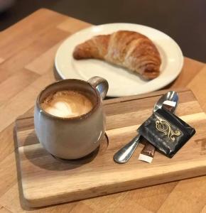 a cup of coffee and a croissant on a wooden tray at Stryn Kaffebar & Vertshus in Stryn