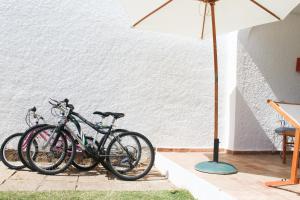 due biciclette parcheggiate accanto a un muro bianco con un ombrello di Villa Pedras D'el Rei a Tavira