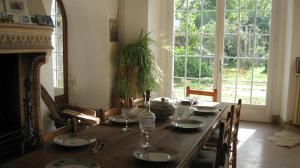 a dining room with a wooden table and a large window at Le Petit Bois in Château-la-Vallière