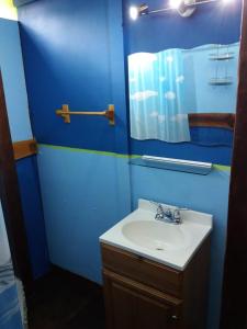 a blue bathroom with a sink and a mirror at Casita Rio Indio in Nombre de Dios