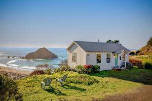 Greenwood Beach Cottage في Elk: منزل صغير مع كرسيين أمام المحيط