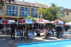 a group of people sitting at tables and umbrellas by a pool at Hôtel - Appartement " LES FLOTS BLEU " in Antananarivo