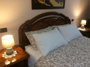 un letto con testata in legno e due tavoli con lampade; di Sunny Hill's Home a Monterotondo