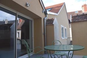 a glass table and chairs on a balcony with a table at Gîte Fassardy in Châteauroux